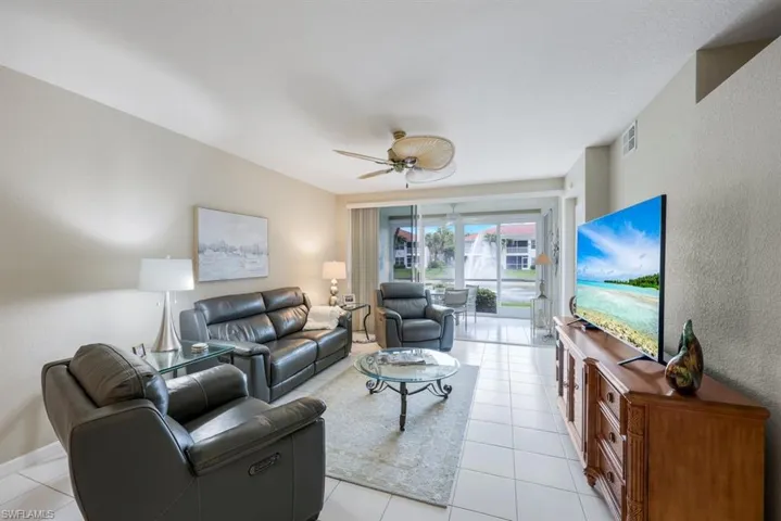 Living room with light tile patterned floors, a textured wall, and ceiling fan