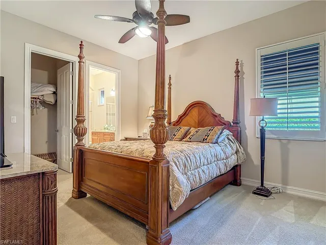 Bedroom featuring light carpet, ensuite bathroom, a ceiling fan, and baseboards