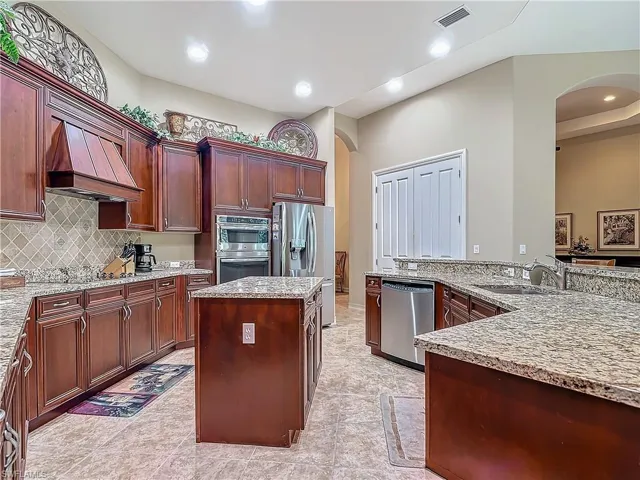 Kitchen with arched walkways, premium range hood, a sink, appliances with stainless steel finishes, and a center island