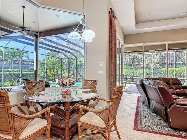 Dining area with a sunroom, light tile patterned flooring, a wealth of natural light, and ceiling fan with notable chandelier