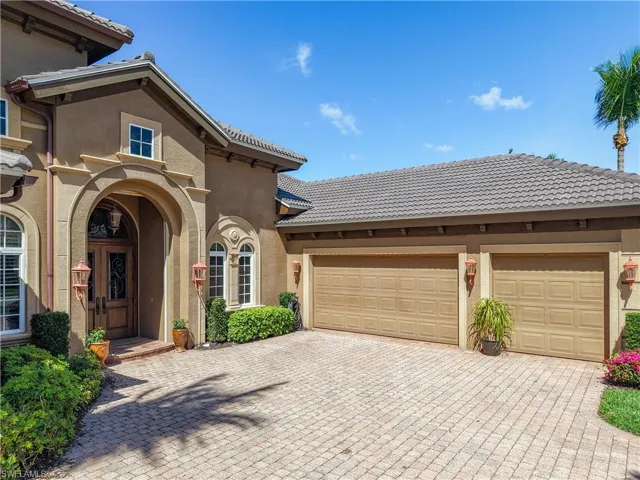 View of front of property featuring an attached garage, a tile roof, decorative driveway, and stucco siding
