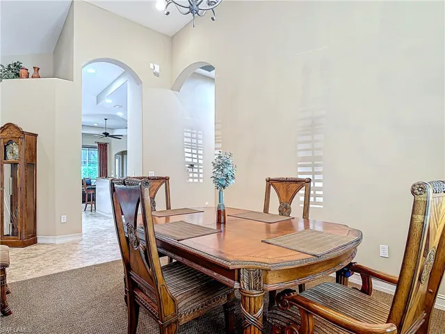 Carpeted dining room featuring a ceiling fan, arched walkways, and baseboards
