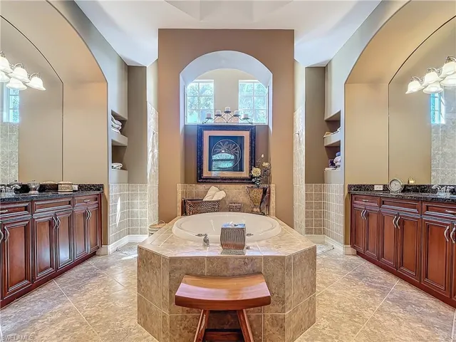 Full bath featuring a sink, two vanities, plenty of natural light, and a garden tub