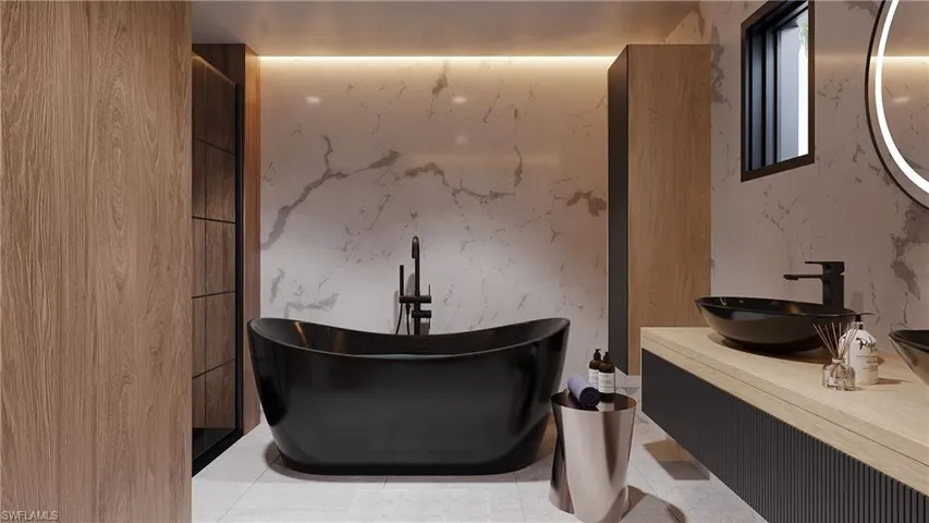 Bathroom featuring vanity, a soaking tub, and stone wall