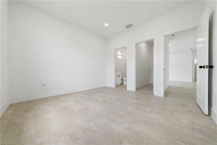 Unfurnished bedroom featuring a spacious closet, recessed lighting, and ensuite bathroom