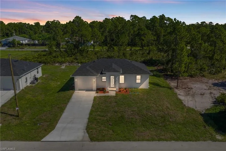 View of front facade featuring concrete driveway, a front yard, a garage, and stucco siding