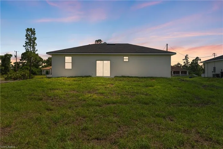 Back of house featuring a lawn and stucco siding