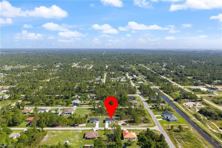 Aerial overview of property's location featuring nearby suburban area and a forest