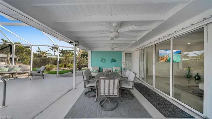 Sunroom / solarium with outdoor dining area, a patio, a ceiling fan, an outdoor living space, and beam ceiling