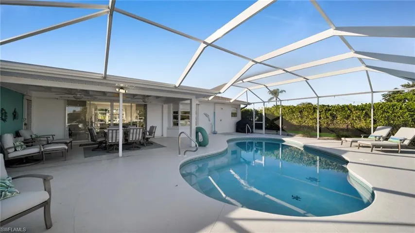 Outdoor pool featuring glass enclosure, a sunroom, a patio area, outdoor dining space, and an outdoor living space