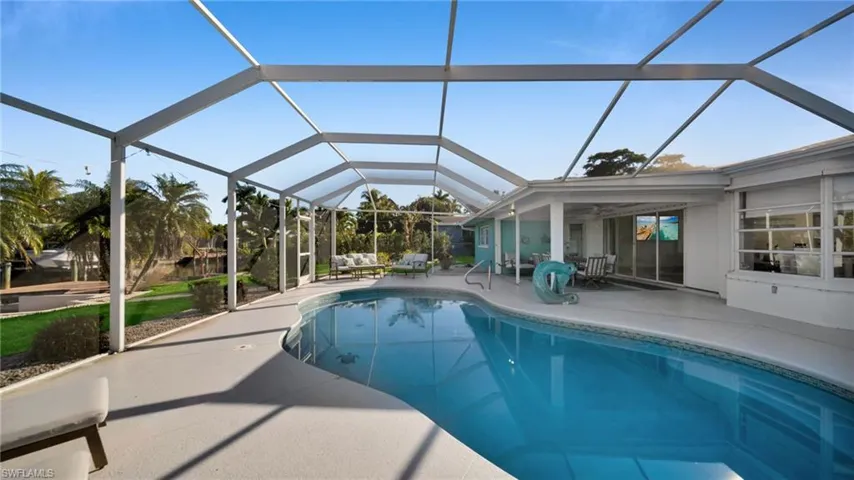 Swimming pool featuring a sunroom, a lanai, and a patio