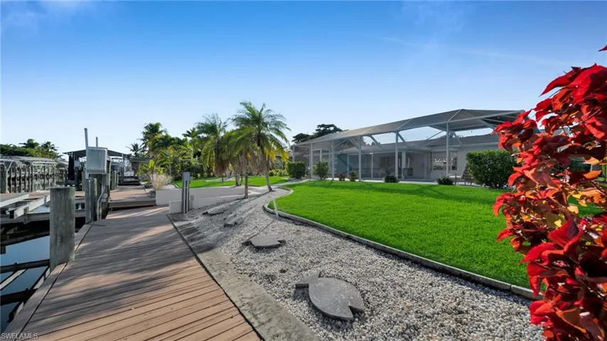 View of home's community featuring a lawn, a dock, a sunroom, and boat lift