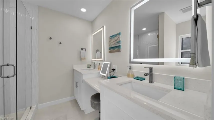 Full bath with a marble finish shower, two vanities, and recessed lighting
