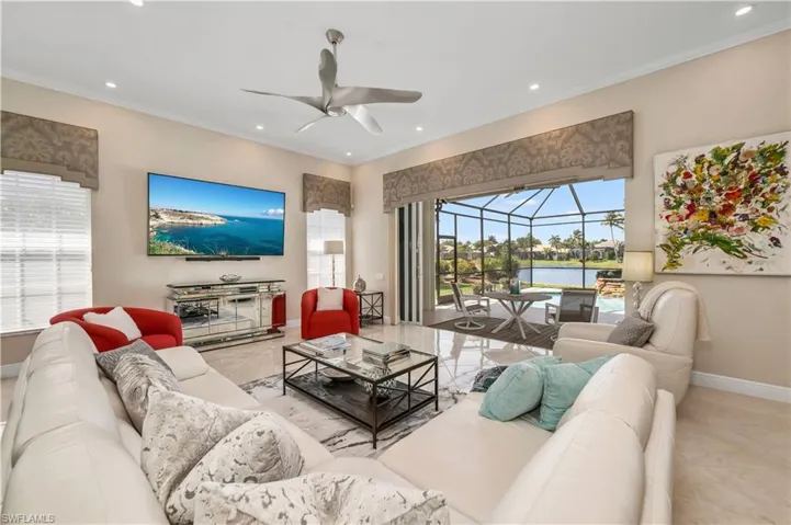 Living room featuring ornamental molding, light tile patterned floors, and ceiling fan