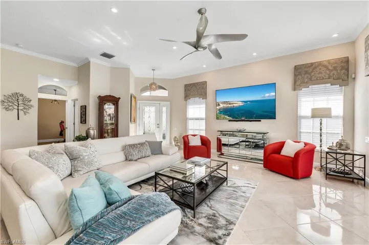 Living room with ceiling fan, a healthy amount of sunlight, crown molding, and light tile patterned floors