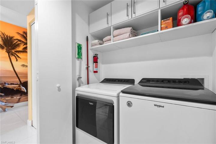 Laundry room with upgraded washer and dryer and custom cabinets and storage