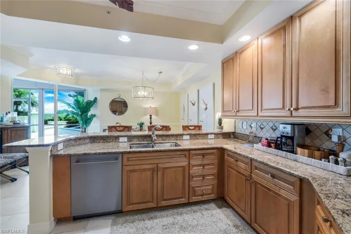 Kitchen with a tray ceiling, kitchen peninsula, backsplash, sink, and dishwasher
