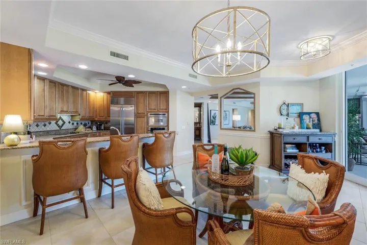 Dining area featuring a raised ceiling, ornamental molding, light tile floors, and ceiling fan with notable chandelier.Sometimes used as Family/TV room.