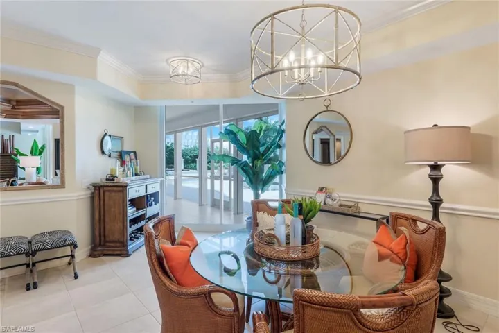 Tiled dining space featuring an inviting chandelier and crown molding