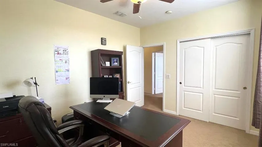 Carpeted office space featuring ceiling fan