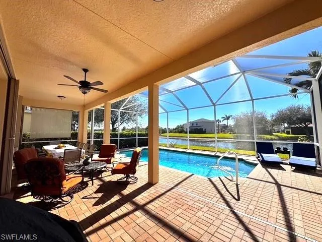 View of swimming pool featuring a water view, an outdoor hangout area, a patio area, and glass enclosure