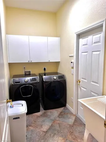 Clothes washing area featuring cabinets and washer and dryer