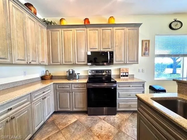 Kitchen with light stone countertops, stainless steel appliances, and sink