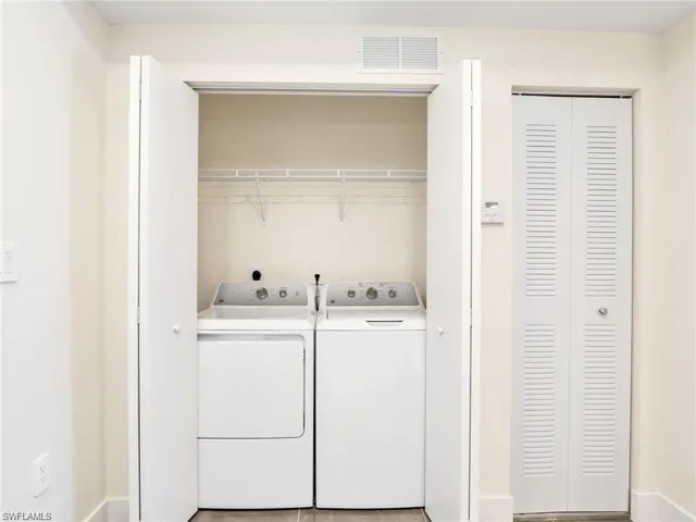 Clothes washing area featuring laundry area, visible vents, and washer and clothes dryer