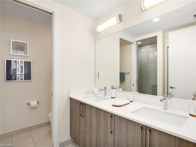 Full bathroom featuring toilet, a stall shower, a sink, and tile patterned flooring