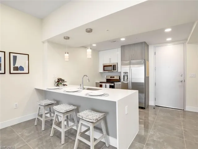 Kitchen with stainless steel appliances, a peninsula, a kitchen breakfast bar, and a sink