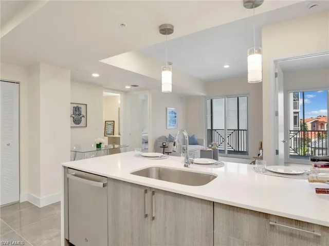 Kitchen with open floor plan, light countertops, decorative light fixtures, dishwasher, and a sink