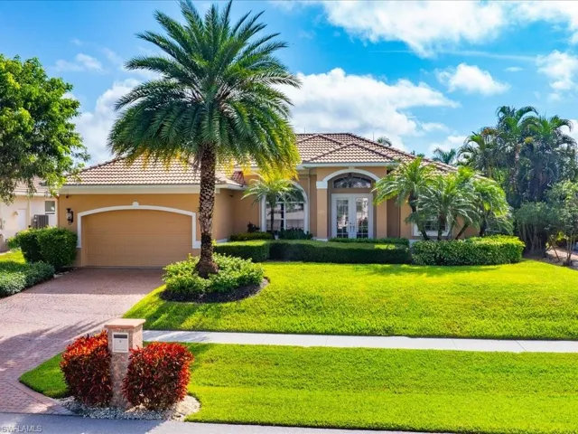 Marco home featuring french doors, a garage, and a front lawn