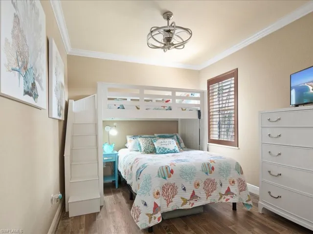 Bedroom with ornamental molding and wood-type flooring