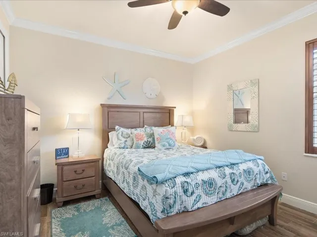 Bedroom with dark wood-type flooring, ceiling fan, and crown molding