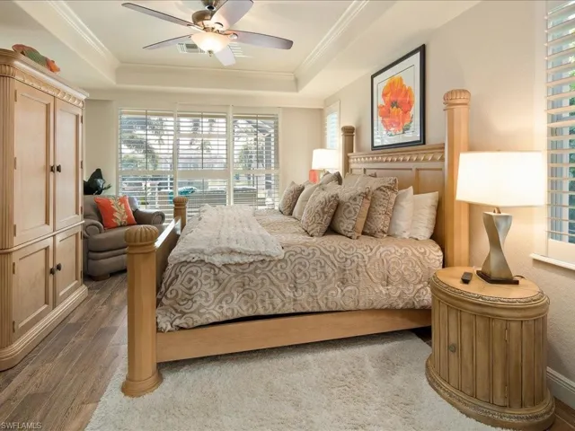 Bedroom with ceiling fan, dark hardwood / wood-style floors, a raised ceiling, and ornamental molding