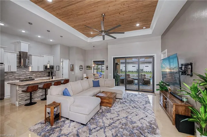 Living room featuring custom wood tray ceiling, a towering ceiling, large ceiling fan, recessed lighting,