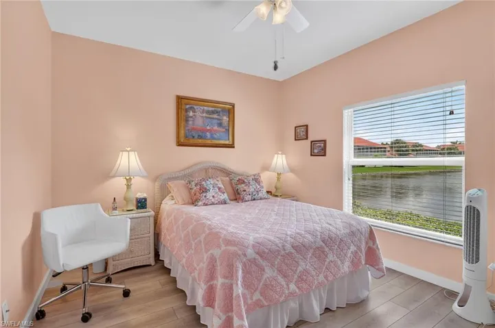 Bedroom with wood finished floors, ceiling fan, and a water view