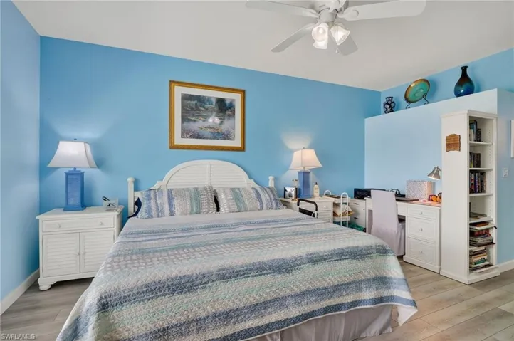 Bedroom with light wood-style floors, ceiling fan, and an office area