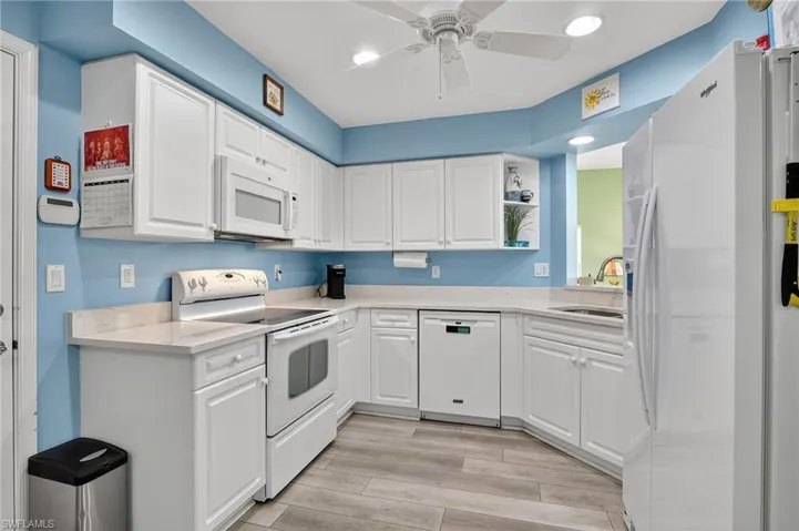 Kitchen with white appliances, white cabinets, wood tiled floors, recessed lighting, and ceiling fan