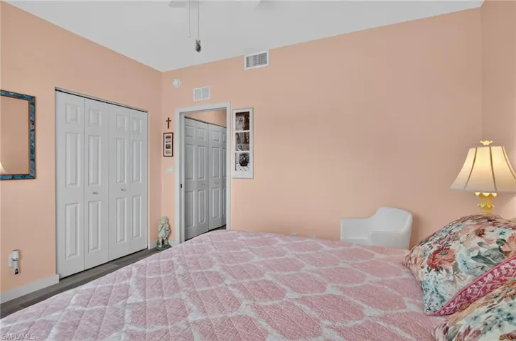 Bedroom with multiple closets, a ceiling fan, and wood finished floors