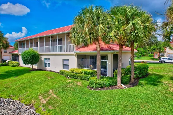 Back of property featuring a sunroom, a lawn, stucco siding, and a tile roof
