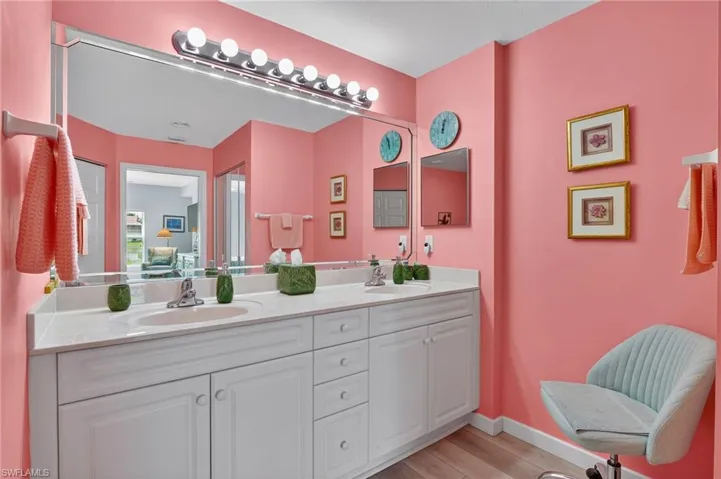 Full bath featuring double vanity and light wood-style flooring