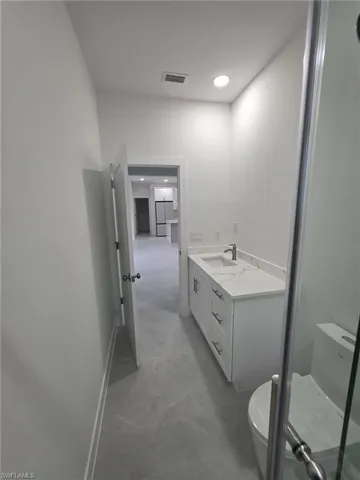 Bathroom featuring a stall shower, baseboards, visible vents, toilet, and vanity