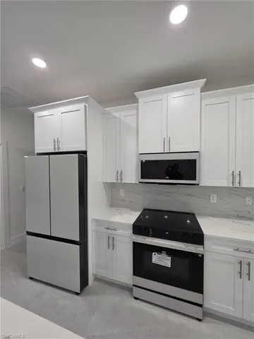 Kitchen featuring white cabinetry, range with electric cooktop, and freestanding refrigerator