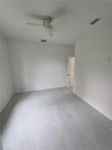 Empty room featuring baseboards, visible vents, and a ceiling fan