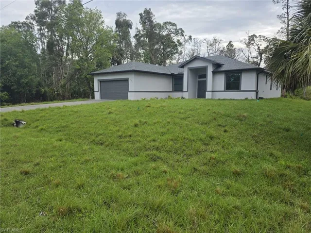 Prairie-style house featuring a garage, a front yard, driveway, and stucco siding
