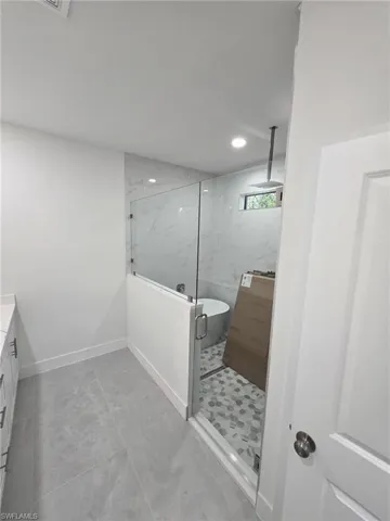 Bathroom featuring a marble finish shower, recessed lighting, a freestanding bath, vanity, and baseboards