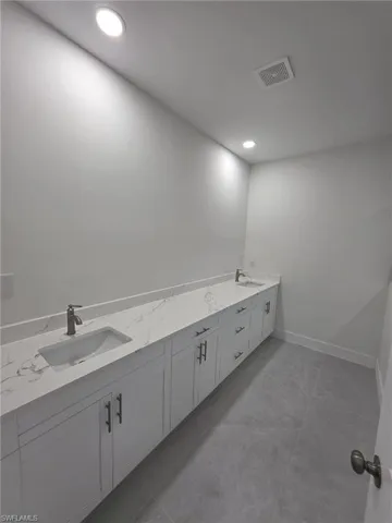 Bathroom featuring double vanity, baseboards, visible vents, and a sink