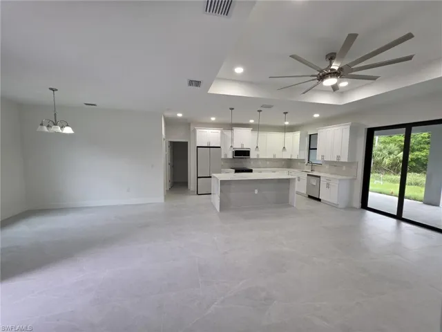 Kitchen featuring stainless steel appliances, open floor plan, light countertops, and white cabinetry