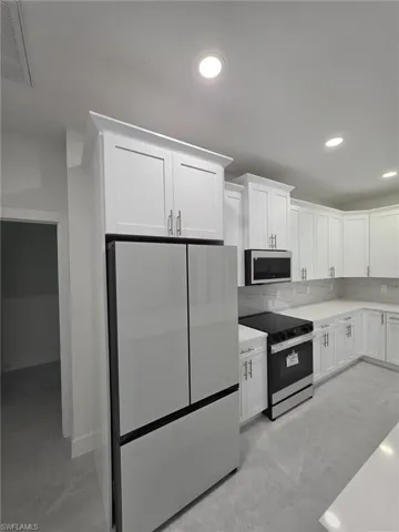 Kitchen featuring visible vents, appliances with stainless steel finishes, light countertops, white cabinetry, and backsplash